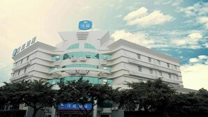 Ein mehrstöckiges Gebäude mit einer auffälligen blauen Beschilderung oben, vermutlich ein Hotel oder ähnliche Einrichtung.