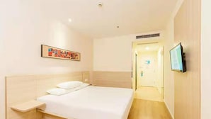 Ein Hotelzimmer mit einem Bett, einem Nachttisch, einem Fernseher und einer Tür zu einem anderen Raum.