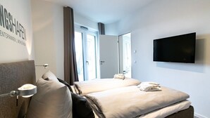 Una habitación de hotel moderna con una cama grande, un televisor de pantalla plana y vistas al exterior.