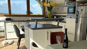 A modern kitchen with a built-in oven, a sink, and a dining area with a table set for two.