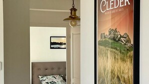 A bedroom with a bed, a framed picture on the wall, and a hallway leading to another room.