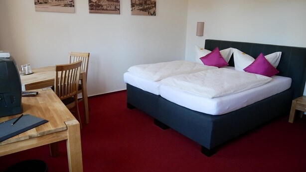 A bedroom with a bed, a desk, and chairs. - Hotel Garni Brauhof Niederwiesa (Niederwiesa)