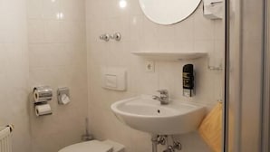 A bathroom with a toilet, sink, and mirror. - Hotel Garni Brauhof Niederwiesa (Niederwiesa)