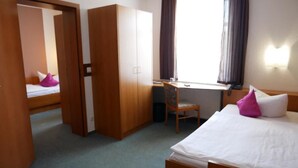 A hotel room with a bed, a desk, a chair, a wardrobe, and a window with curtains. - Hotel Garni Brauhof Niederwiesa (Niederwiesa)