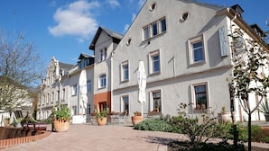 A hotel with a courtyard, potted plants, and a sign indicating it is a hotel. - Hotel Garni Brauhof Niederwiesa (Niederwiesa)