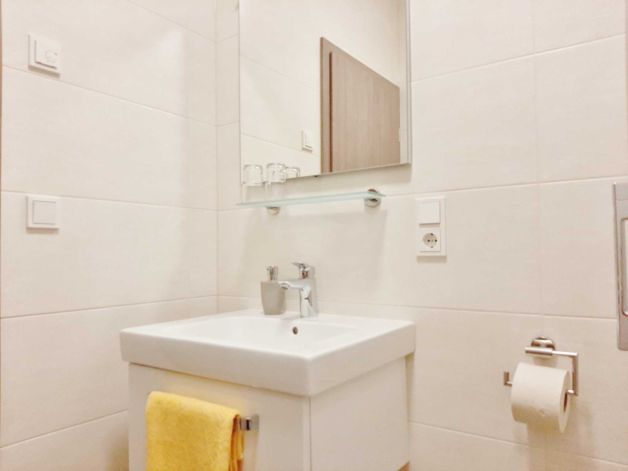 A bathroom with a white sink, mirror, and towel rack.