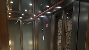 Un ascensor con puertas de vidrio, una pared de piedra y un suelo de baldosas.
