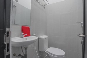 Un baño con un lavamanos blanco, inodoro y una toalla roja sobre el lavamanos.