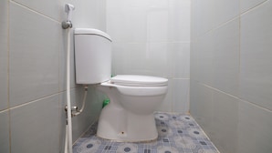 Un baño pequeño y limpio con inodoro, zona de lavado de manos y un cartel que indica prohibido fumar.
