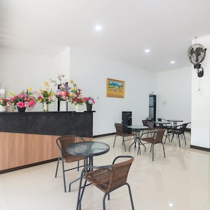 Una zona de recepción con mostrador, sillas, mesas y un cuadro en la pared.