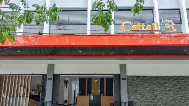 Entrada de hotel com toldo vermelho e uma placa com a inscrição 'Cattail'.
