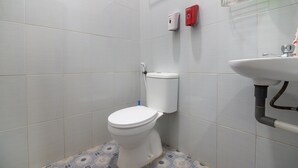 Un baño con inodoro, lavabo y dos dispensadores de jabón en la pared.