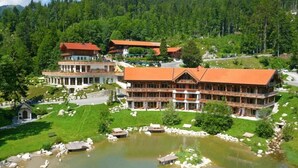 A large, multi-story building with a red roof, surrounded by lush greenery and a lake. - Feuriger Tatzlwurm Berghotel & Spa BW Signature (Oberaudorf)