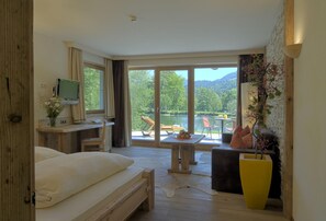 Ein Schlafzimmer mit einem großen Bett, einem Schreibtisch mit Computer und Blick auf einen See und Berge.
