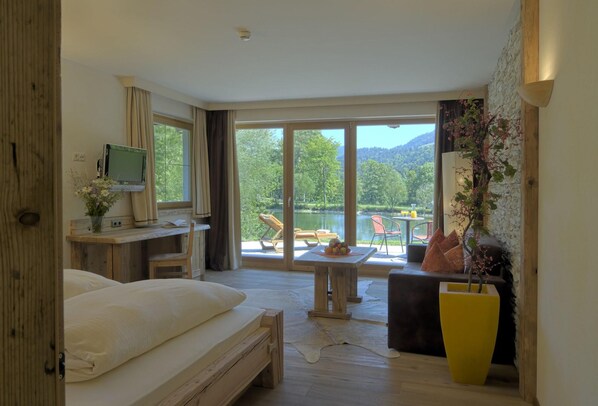 Un dormitorio con una cama grande, un escritorio con computadora y vistas a un lago y montañas.
