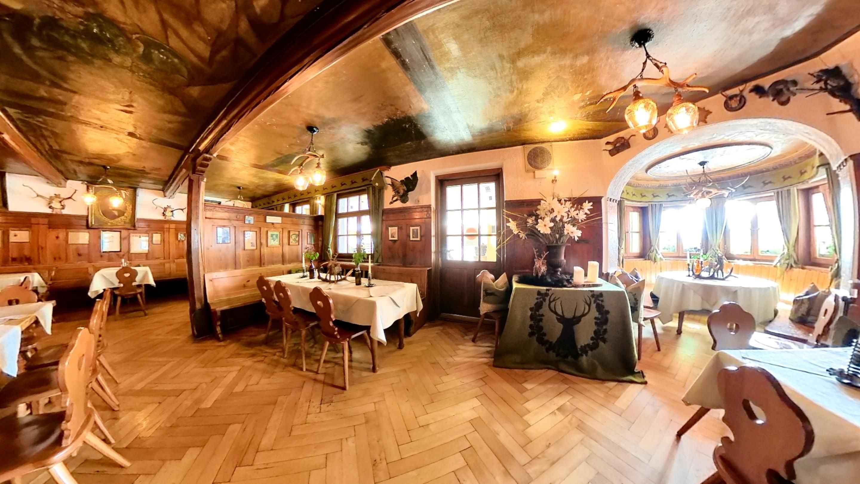 A restaurant with wooden interiors, multiple dining tables, and a herringbone floor pattern.