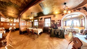 Un restaurant au décor intérieur en bois, doté de nombreuses tables et dont le sol présente un motif en chevrons.