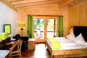 A wooden room with a bed, a desk, a chair, and a table. There is a view through the door to the outside. - Feuriger Tatzlwurm Berghotel & Spa BW Signature (Oberaudorf)