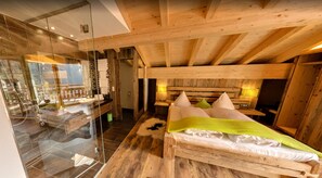A wooden cabin interior with a glass-walled bathroom, a bed with pillows, and a wooden ceiling. - Feuriger Tatzlwurm Berghotel & Spa BW Signature (Oberaudorf)