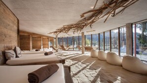 Une salle de spa aux murs en bois, dotée de grandes fenêtres et d’un plafond orné de branches naturelles.