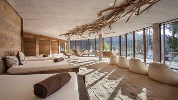 A spa room with wooden walls, large windows, and a ceiling with natural branches.