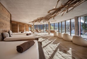 A spa room with wooden walls, large windows, and a ceiling with natural branches. - Feuriger Tatzlwurm Berghotel & Spa BW Signature (Oberaudorf)