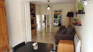 A modern living room with a sofa, a dining table, and a TV on a wooden cabinet.