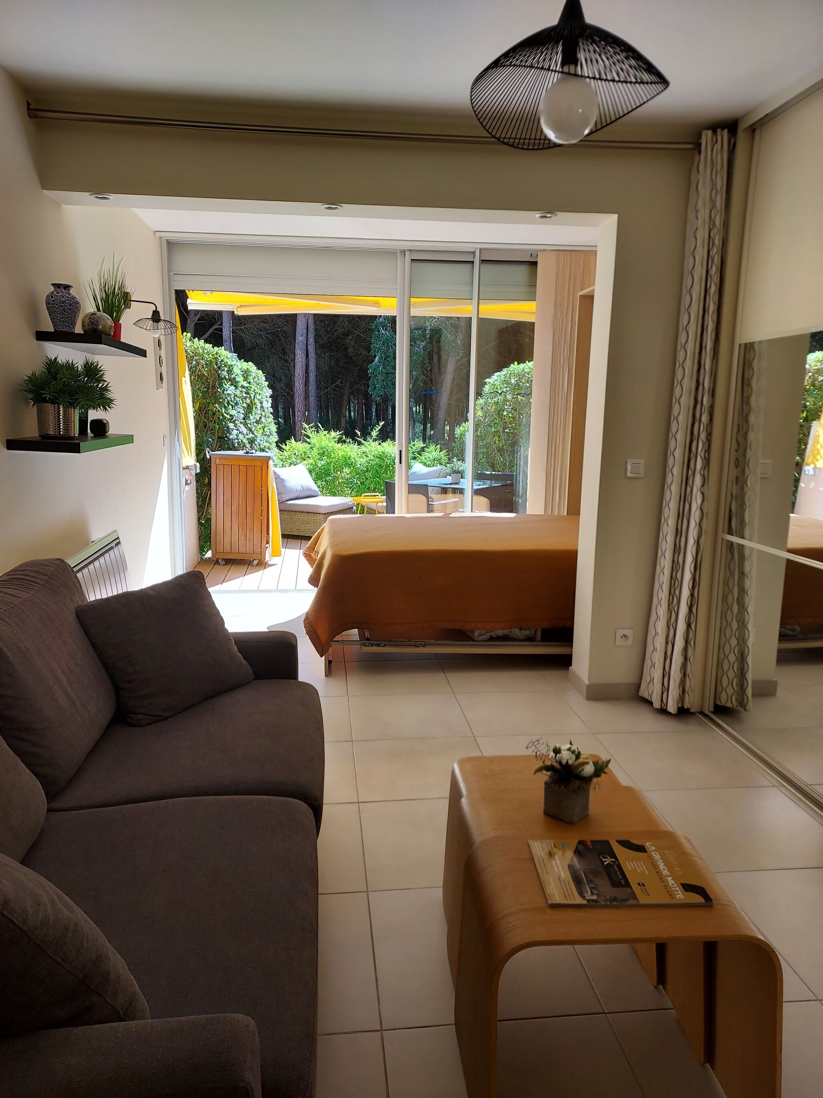 Een moderne woonkamer met een bank, een salontafel en uitzicht op een tuin door grote schuifdeuren.