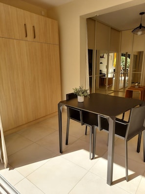 A modern dining area with a wooden cabinet, a dining table with chairs, and a potted plant.