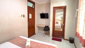 A hotel room with a bed, a desk, a chair, a television, and a door leading to a bathroom. - OYO 3819 Hotel Winotosastro (Yogyakarta)