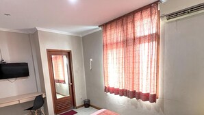 A hotel room with a bed, a desk, a chair, a television, and a window with curtains. - OYO 3819 Hotel Winotosastro (Yogyakarta)