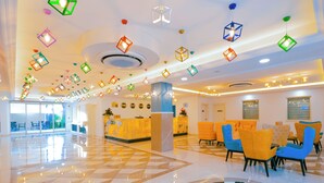 Zona de recepción de un hotel con mostrador de registro, área de asientos con sillas y piso con diseño.
