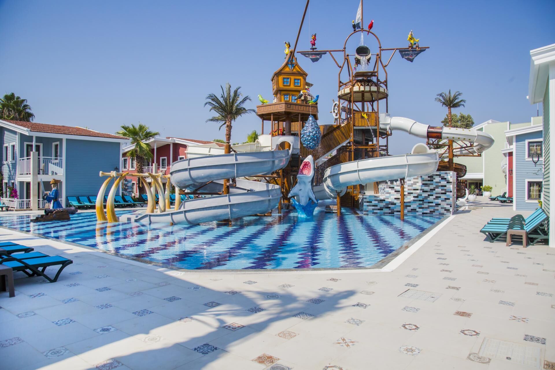 A pool area with water slides, a lifeguard tower, and lounge chairs.