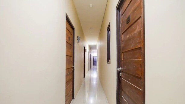 A narrow, well-lit hallway with wooden doors on both sides, leading to a bright room at the end. - OYO 3462 Cimindi Residence (Cimahi)