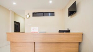 A reception desk with a clock, a flat-screen TV, and a small sign on the wall. - OYO 3462 Cimindi Residence (Cimahi)