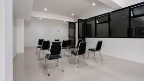 A conference room with white walls, a large window, and several black chairs arranged in a semi-circle. - Super OYO Capital O 3463 Cimahi Guest House (Cimahi)
