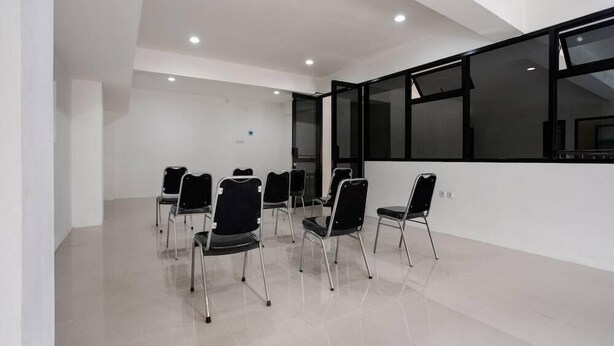 A conference room with white walls, a large window, and several black chairs arranged in a semi-circle. - Super OYO Capital O 3463 Cimahi Guest House (Cimahi)