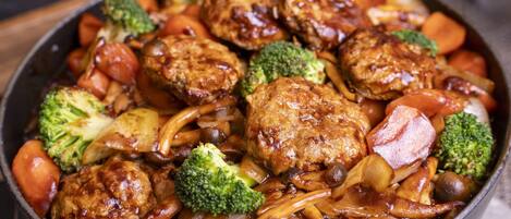 A close-up of a stir-fry dish with chicken, broccoli, and carrots in a pan.