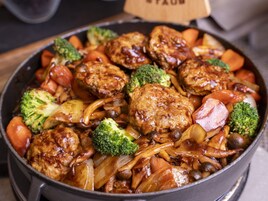 Primer plano de un salteado con pollo, brócoli y zanahorias en una sartén.