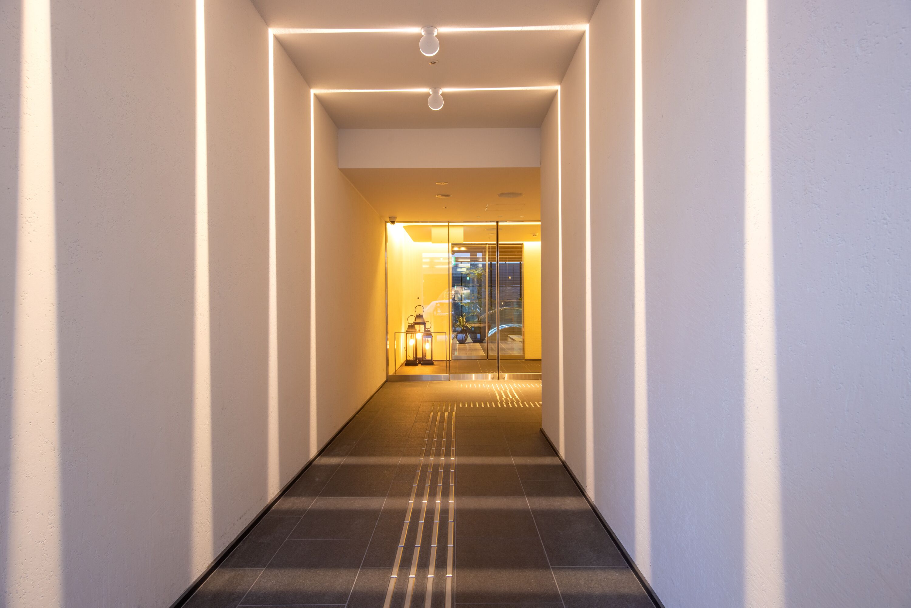 A corridor with a tiled floor and a glass door at the end.