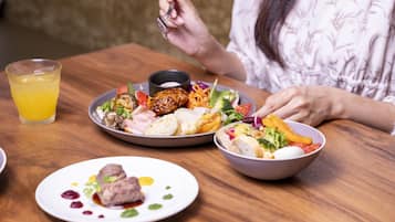 Una mesa de comedor con varios platos, un vaso de jugo de naranja y una persona sentada.