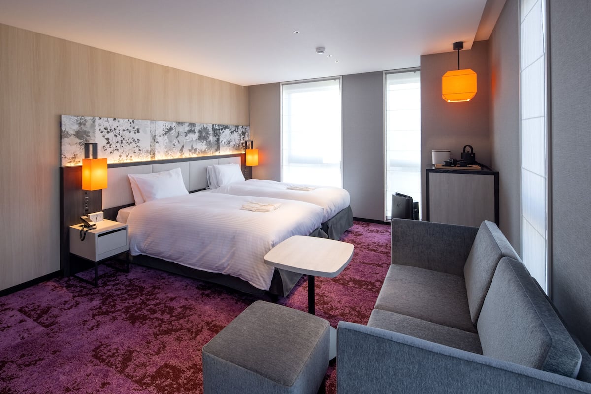 Een moderne hotelkamer met een groot bed, twee nachtkastjes, een bank, een kleine tafel en een nachtkastje.