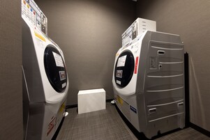 A laundry room with two washing machines and a dryer.
