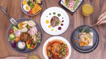 Una mesa de madera con diversos platos, entre ellos ensaladas, carnes y mariscos, acompañados de bebidas y cubiertos.