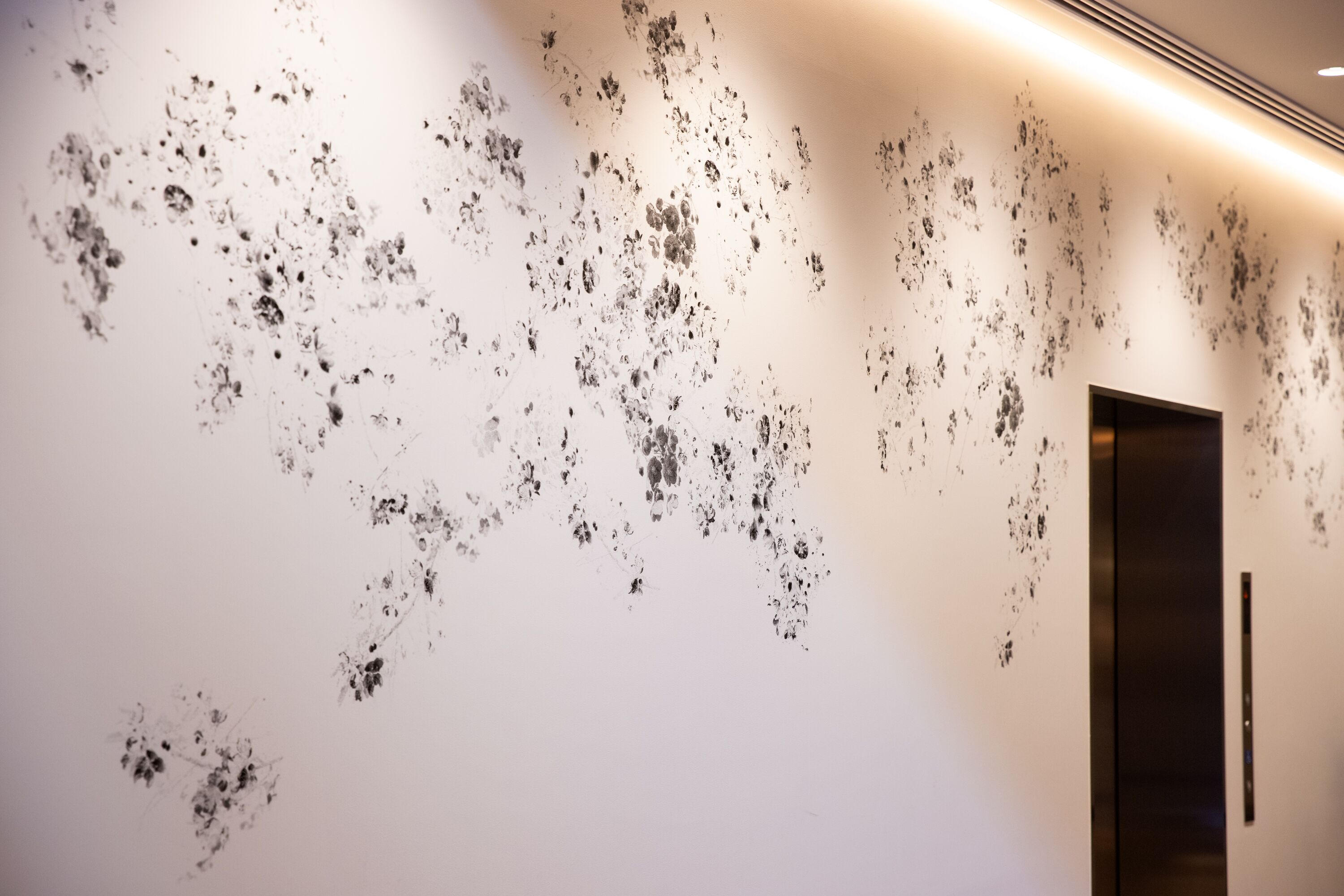 Un mur orné d’un motif de petits points noirs et une porte sur la droite.