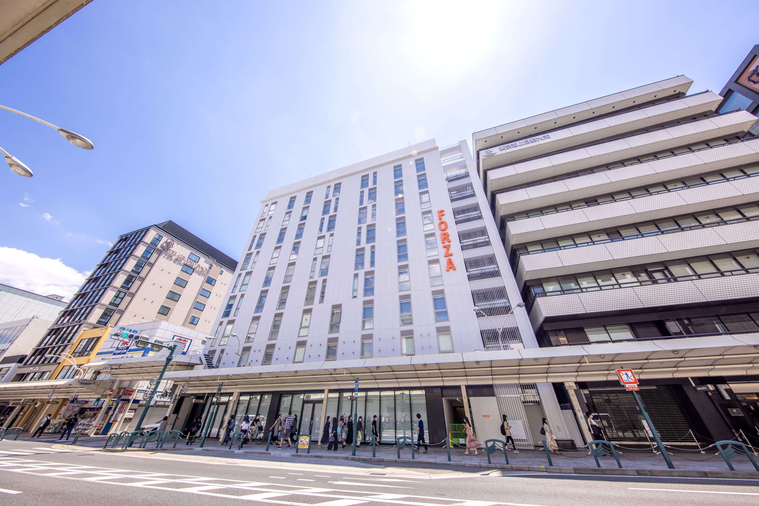 Een modern hotel met een opvallend 'FORZA'-bord, grote ramen en een overdekt entreegebied.