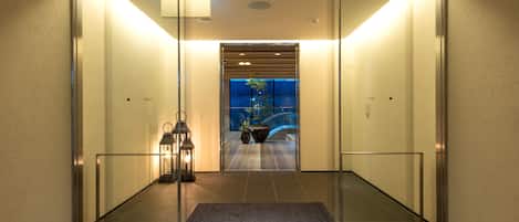A modern elevator entrance with glass doors, a metal frame, and a tiled floor.