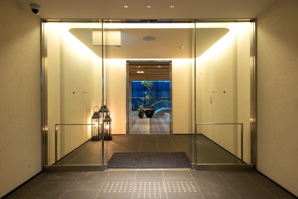 A modern elevator entrance with glass doors, a metal frame, and a tiled floor.