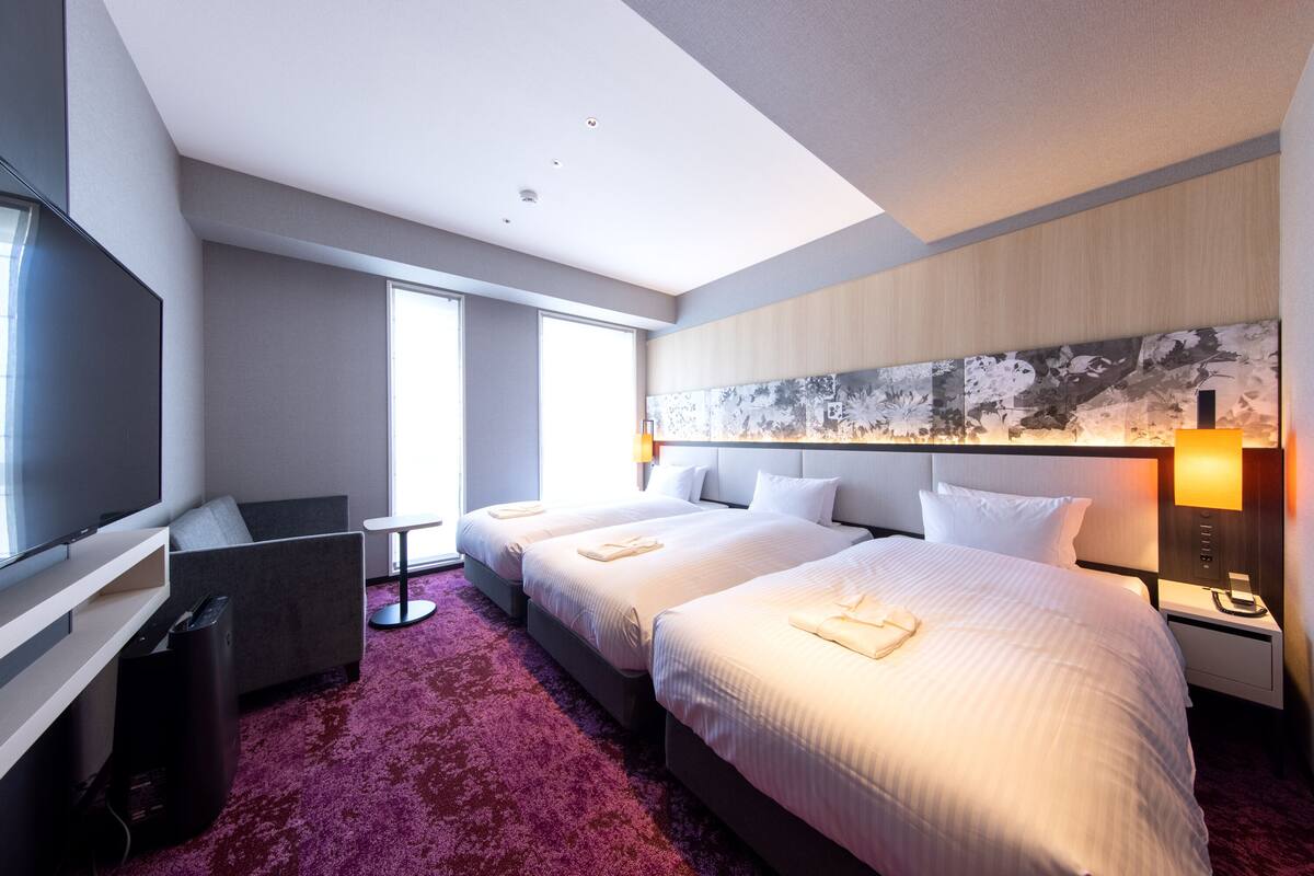 Een hotelkamer met een groot bed, een televisie, een bureau en een raam.