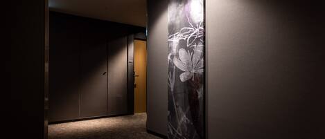 A hallway with a dark wall and a large floral artwork on one side.